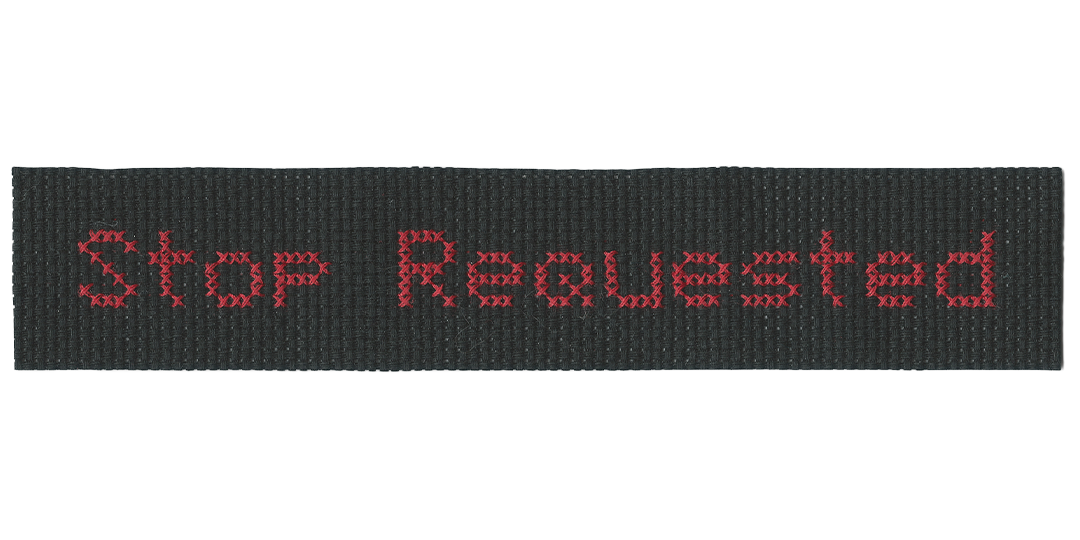 Cross-stitch of red thread on black background, reading 'Stop Requested' in appearance of a bus interior LED marque